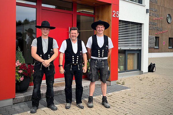 Zimmerei Heinlein übergibt zwei Zimmererhüte an Gesellen vor dem Firmengebäude in Neustadt an der Aisch