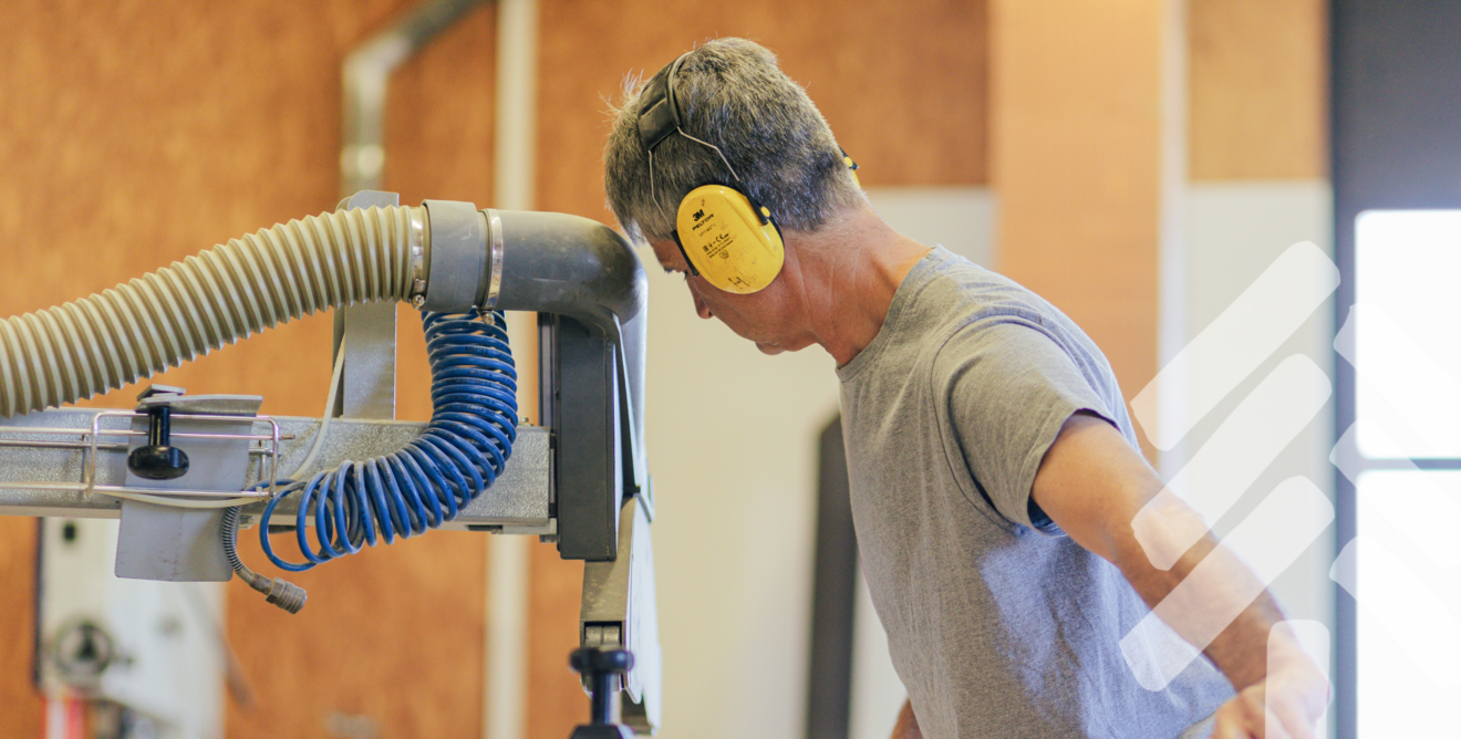 Mitarbeiter arbeitet konzentriert an Holzelement mit moderner Technik