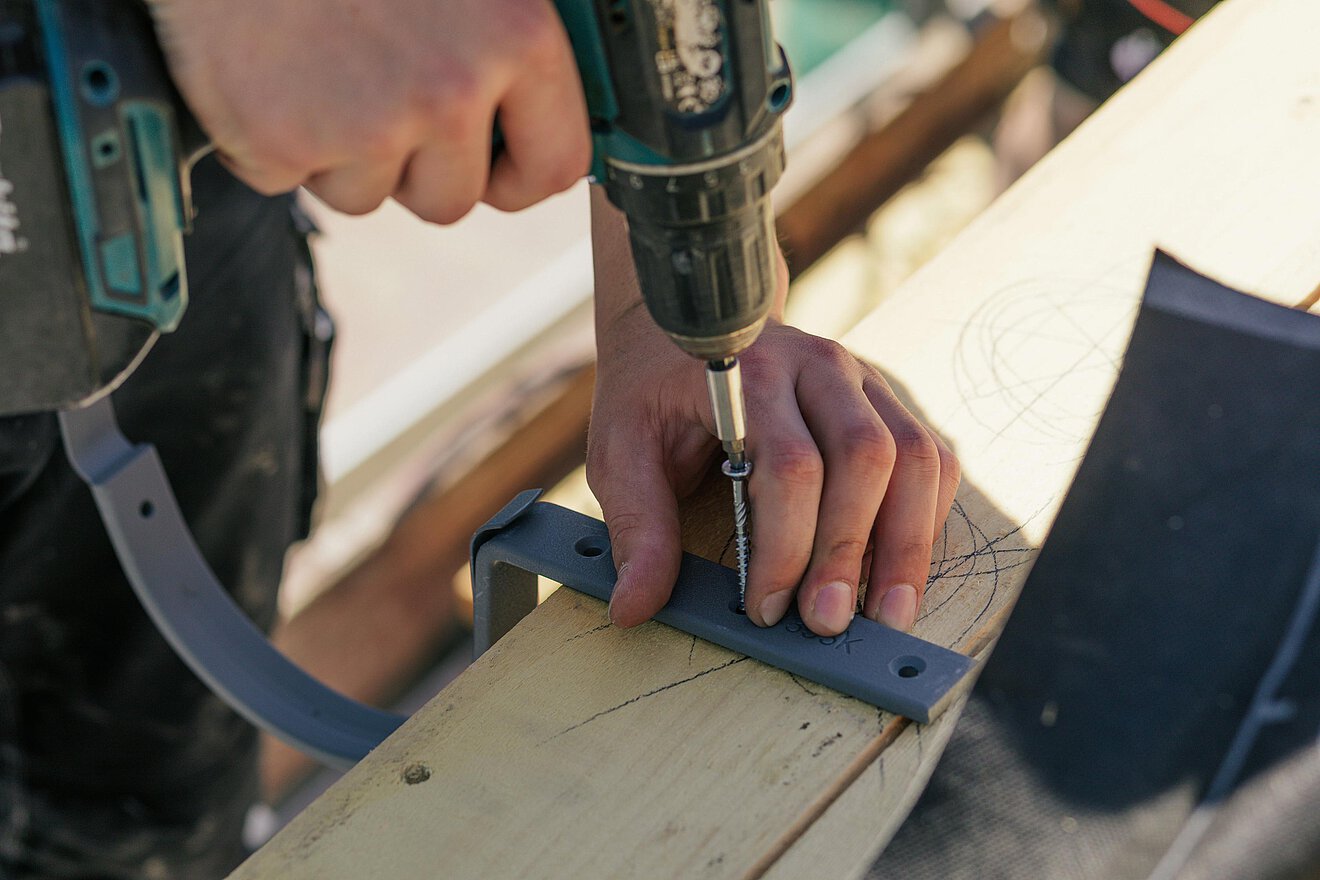 Akkuschrauber fixiert Bauteil auf Holzbalken – präzise Handwerksarbeit