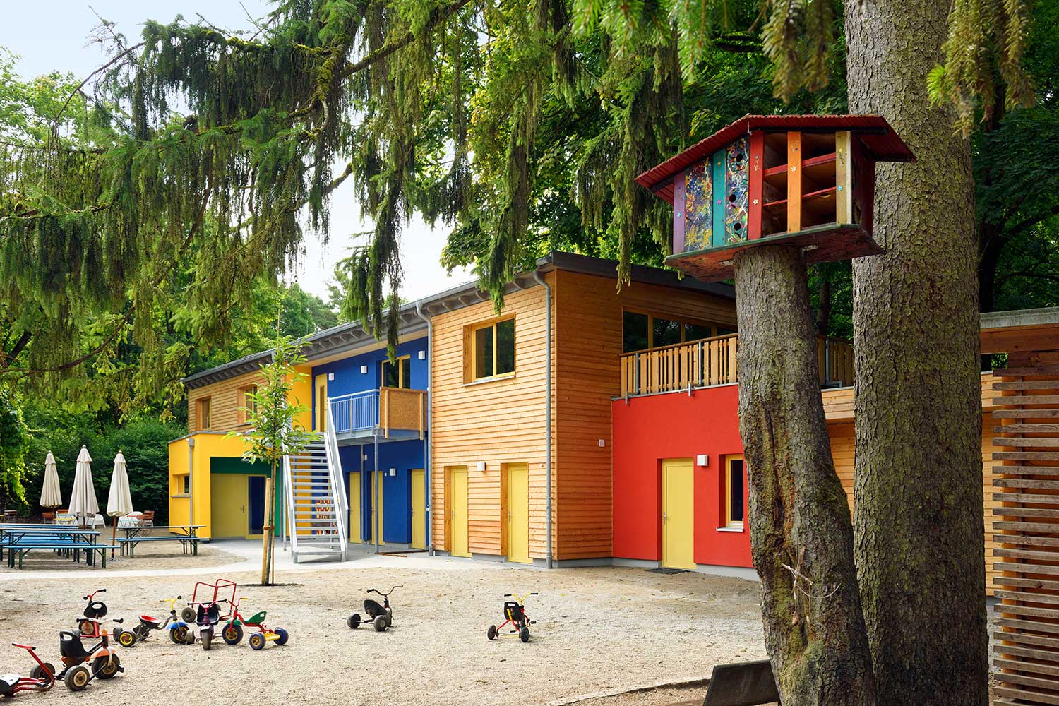 Ansichgs des Innenhofes der "Jugendfarm" mit Spielplatz und bunten Holzgebäuden