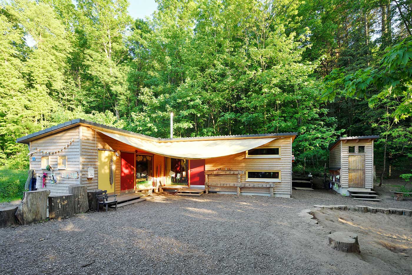 Außenansicht des Waldkindergarten mit Sandkasten