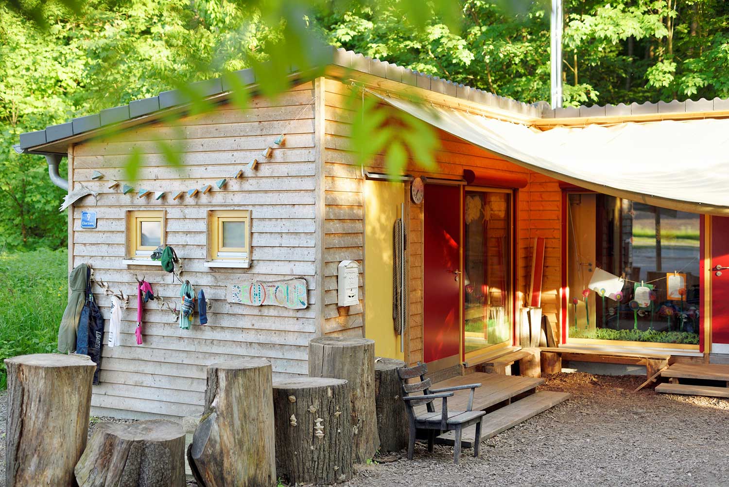 Nahaufnahme des Eingangs des Waldkindergarten mit Kleiderhaken und Baumstämmen